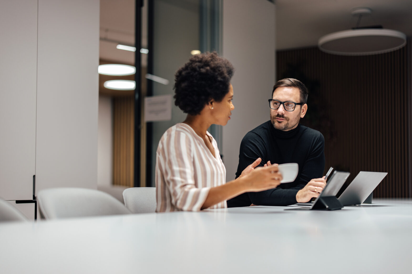 A man and woman talking at a conference room table