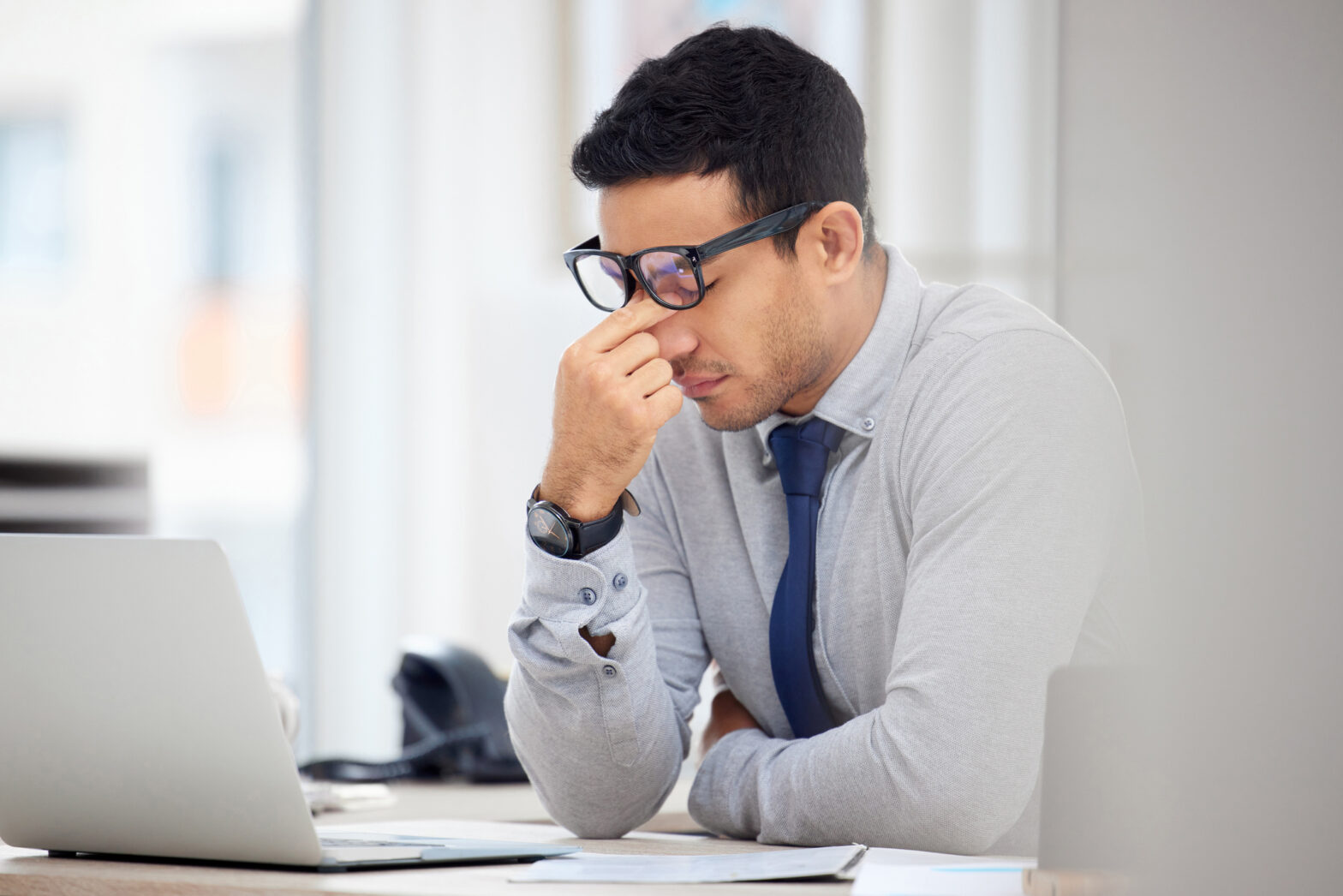 Tired businessman suffering from a headache while working on a laptop at work