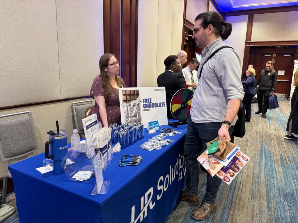 A man and woman converse across a table at the 2024 Waltham Expo