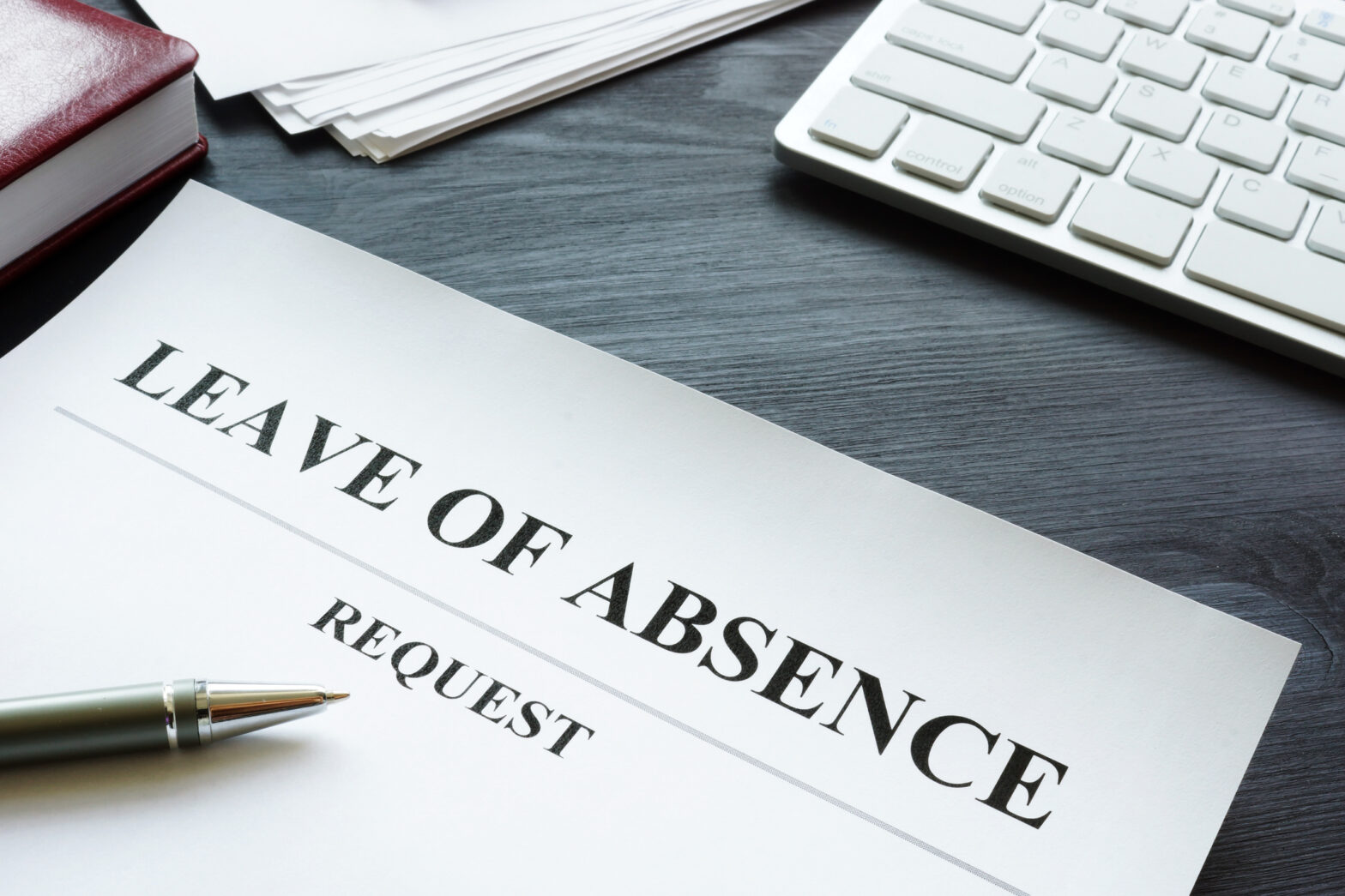 Photo of a piece of paper on a desk that reads "LEAVE OF ABSENCE" at the top of the paper